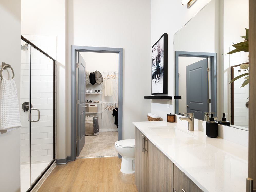Primary bathroom with standing shower, oak cabinetry, white quartz countertops, and ample storage