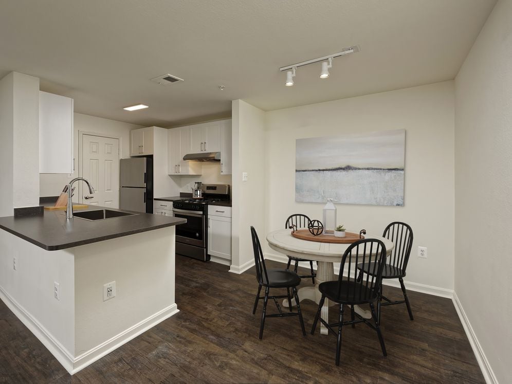 Renovated Package II kitchen and dining area with white cabinetry, dark grey laminate countertops, and stainless steel appliances, and hard surface flooring