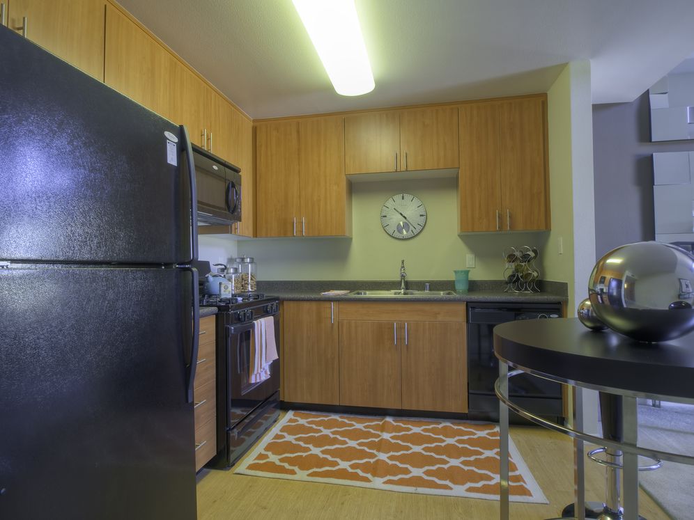 Classic Package kitchen with black appliances, grey speckled laminate countertops, oak cabinetry, and hard surface flooring