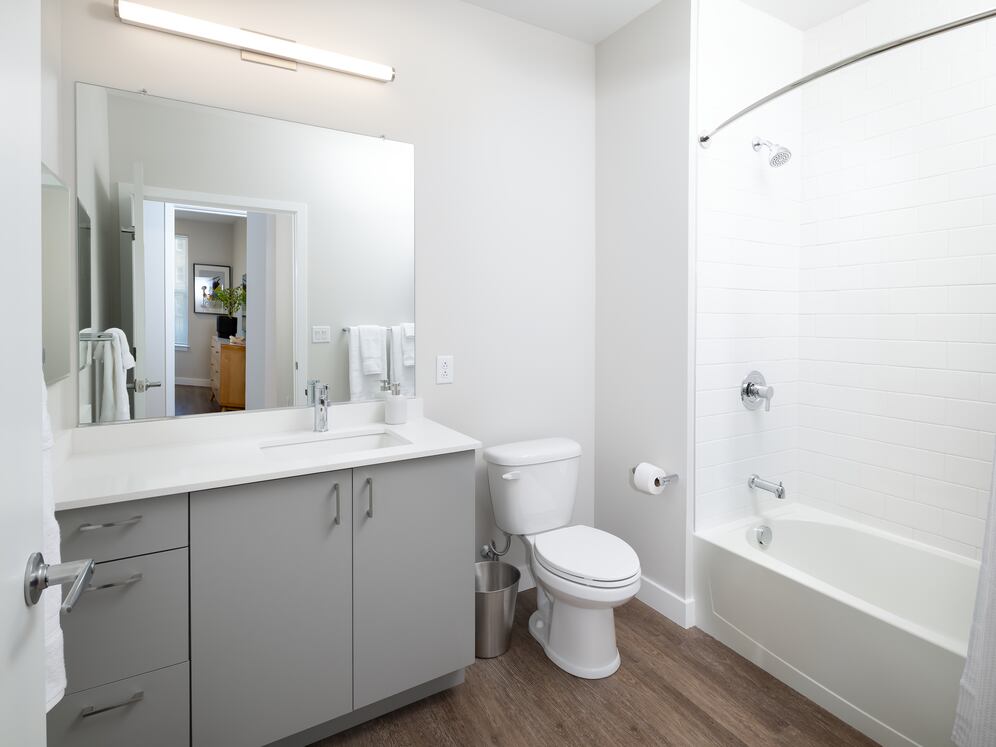 Base Collection bath with white quartz countertop, dark grey cabinetry, and hard surface flooring (representative imagery)