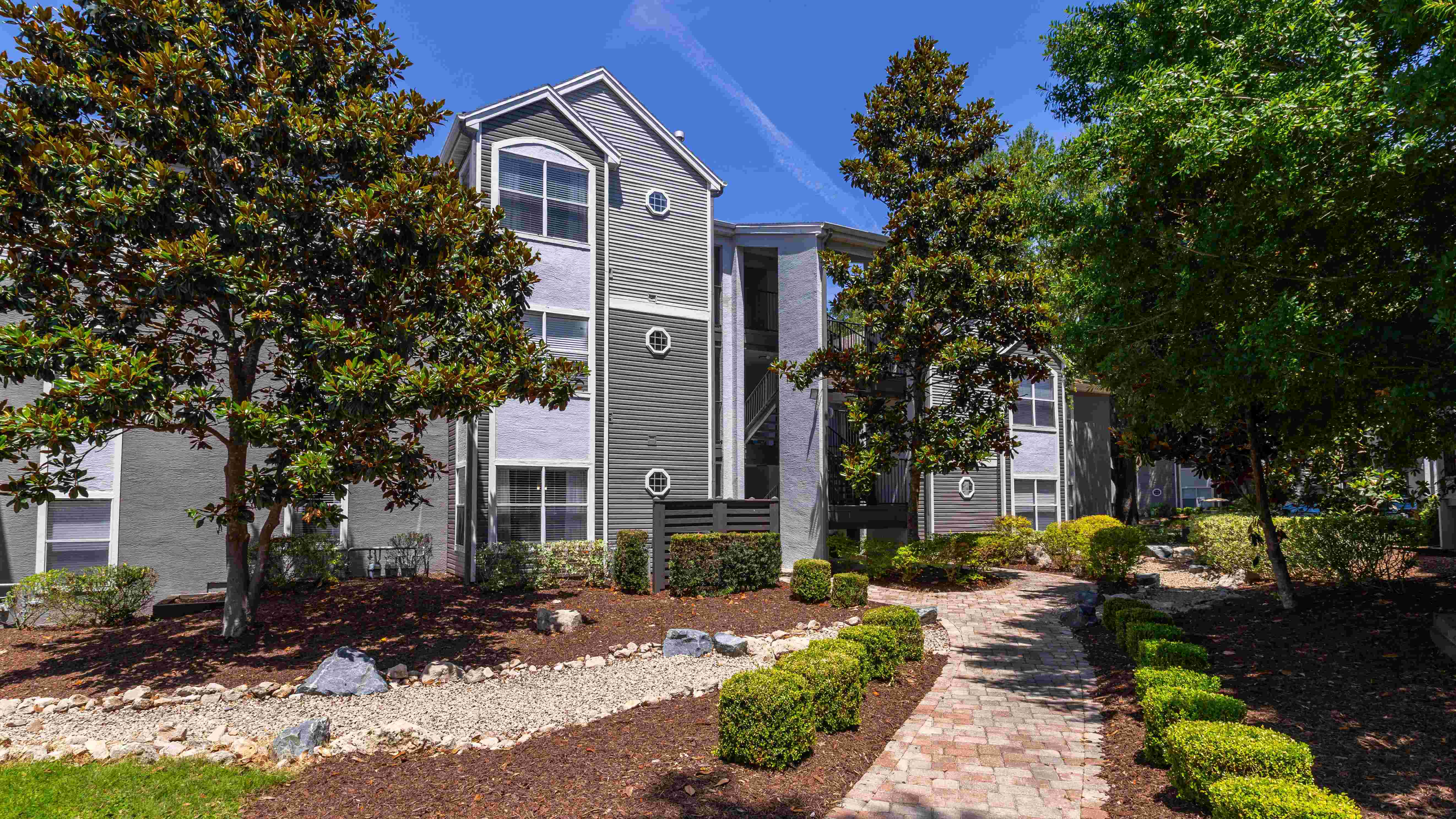 Follow the winding walkway to your apartment home past vibrant greenery and freshly painted buildings.
