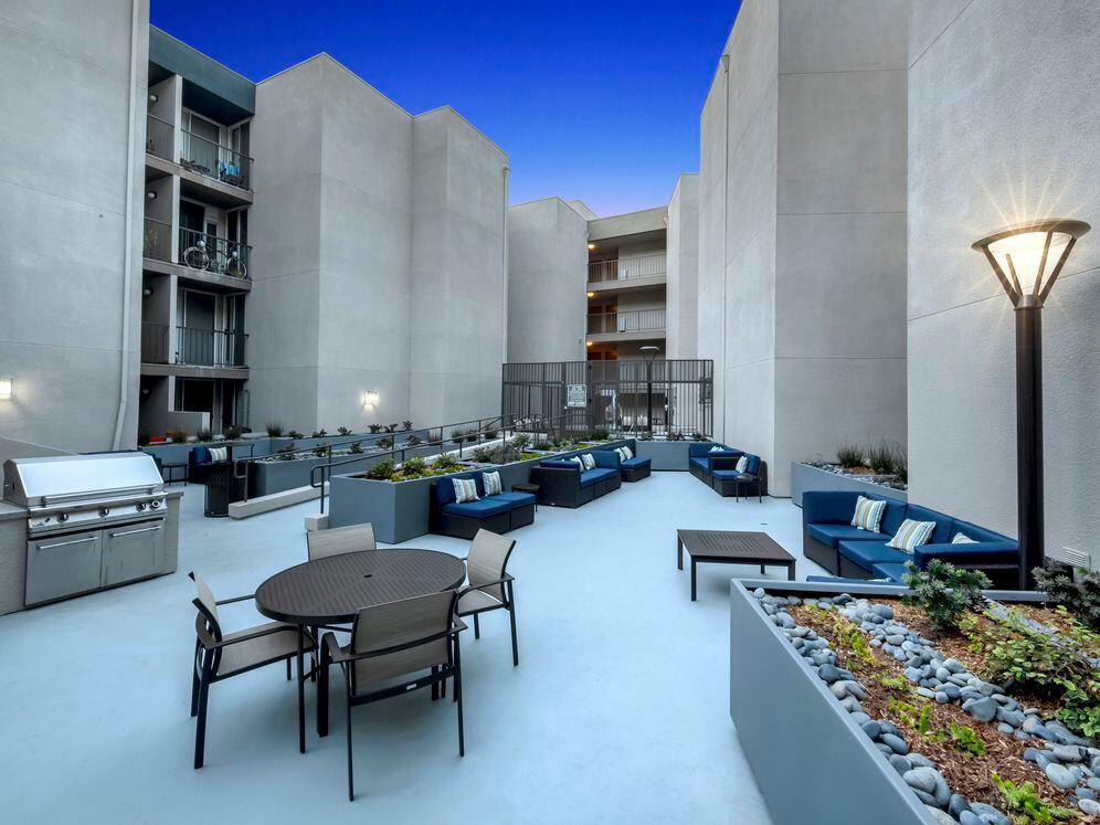 Resident courtyard with barbecue grills, fire pits, and lounge seating at dusk
