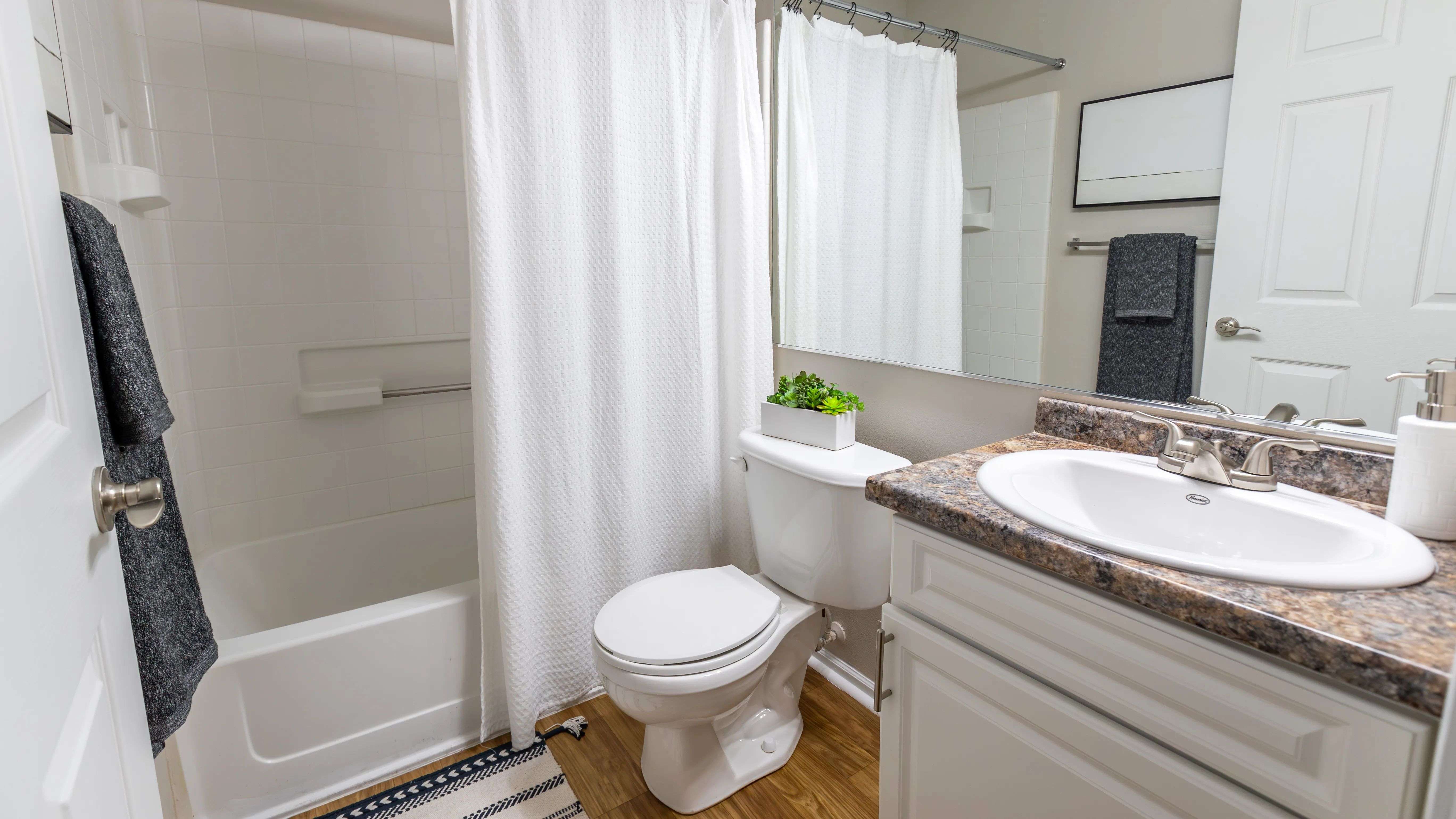 Bathrooms featuring sleek granite-inspired countertops, updated fixtures, a large mirror, and a full-size tub with shower.