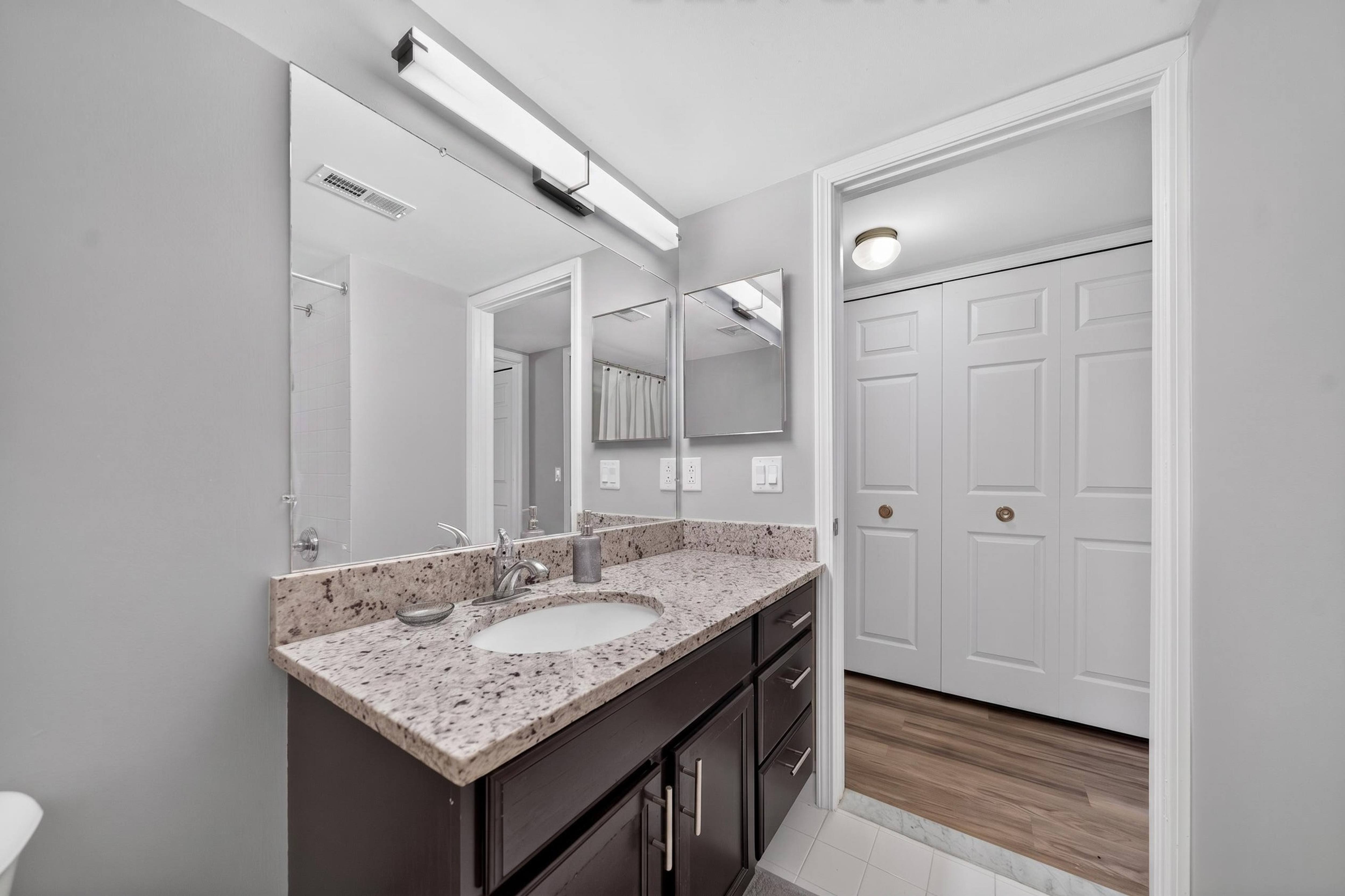 Modern bathroom with large vanity mirror and tub/shower at Lakeside Village Apartments in Clinton Township, MI