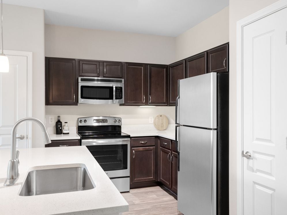 Kitchen with stainless steel appliances, quartz or granite countertops, espresso cabinetry, and hard surface vinyl plank flooring