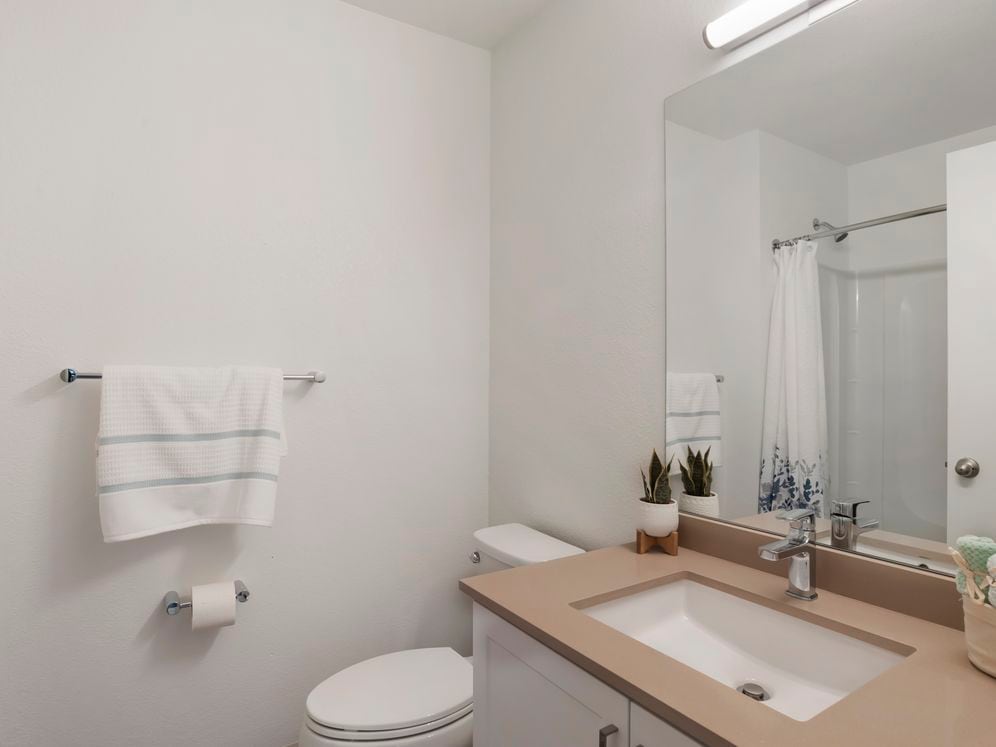 Baths with beige quartz countertops and white cabinetry