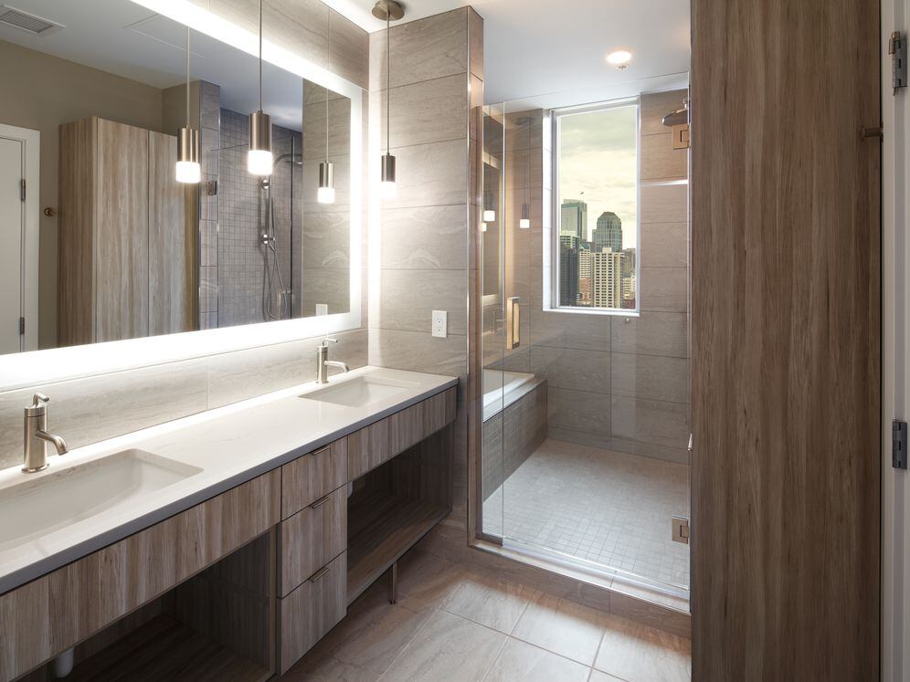 Signature Collection penthouse bath with dual sinks, oak cabinetry, and white quartz countertop.