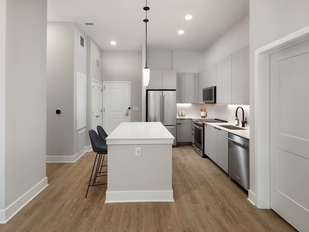 Signature Collection kitchen with stainless steel appliances, light grey cabinetry, marbled quartz countertops and backsplash, under-cabinet lighting, and hard-surface flooring
