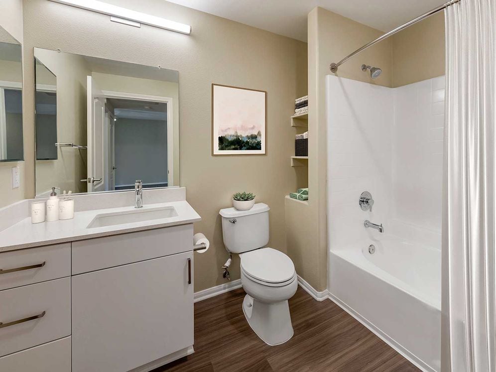Renovated Package I bath with light grey quartz countertops, white cabinetry, and hard surface flooring