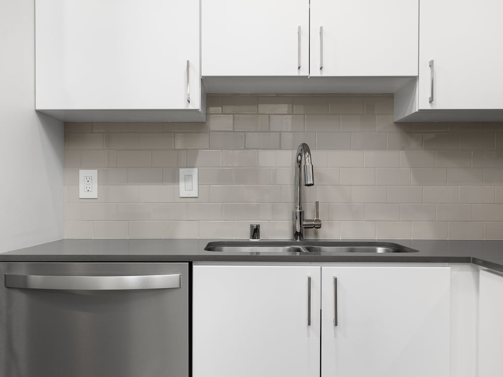 Renovated Package I kitchen with quartz countertops, white cabinetry, stainless steel appliances, hard surface vinyl plank flooring, and tile backsplash