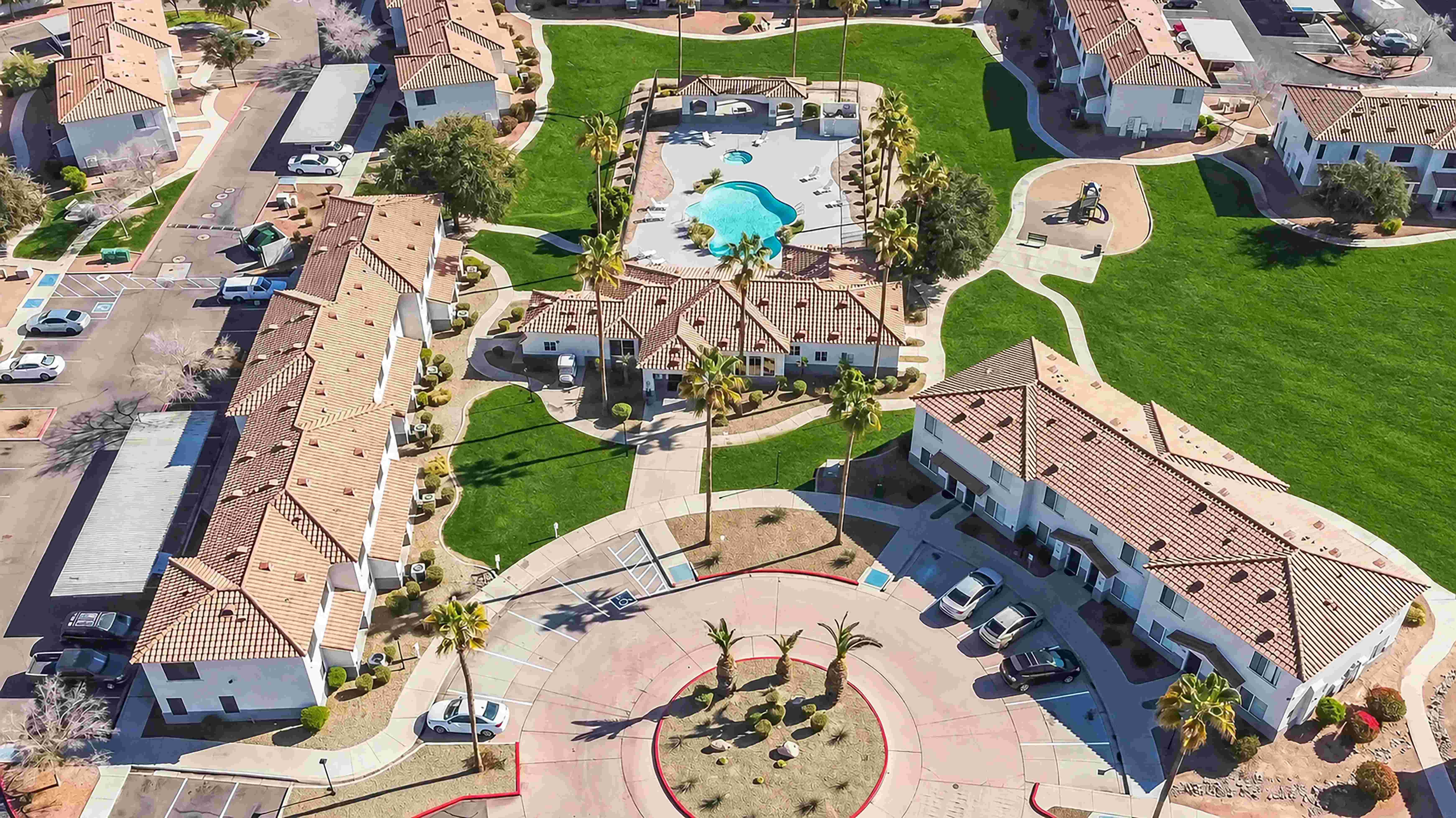 Explore Rancho Del Sol from above, where apartment homes surround expansive green spaces, winding walkways, a refreshing pool, and outdoor recreation areas.