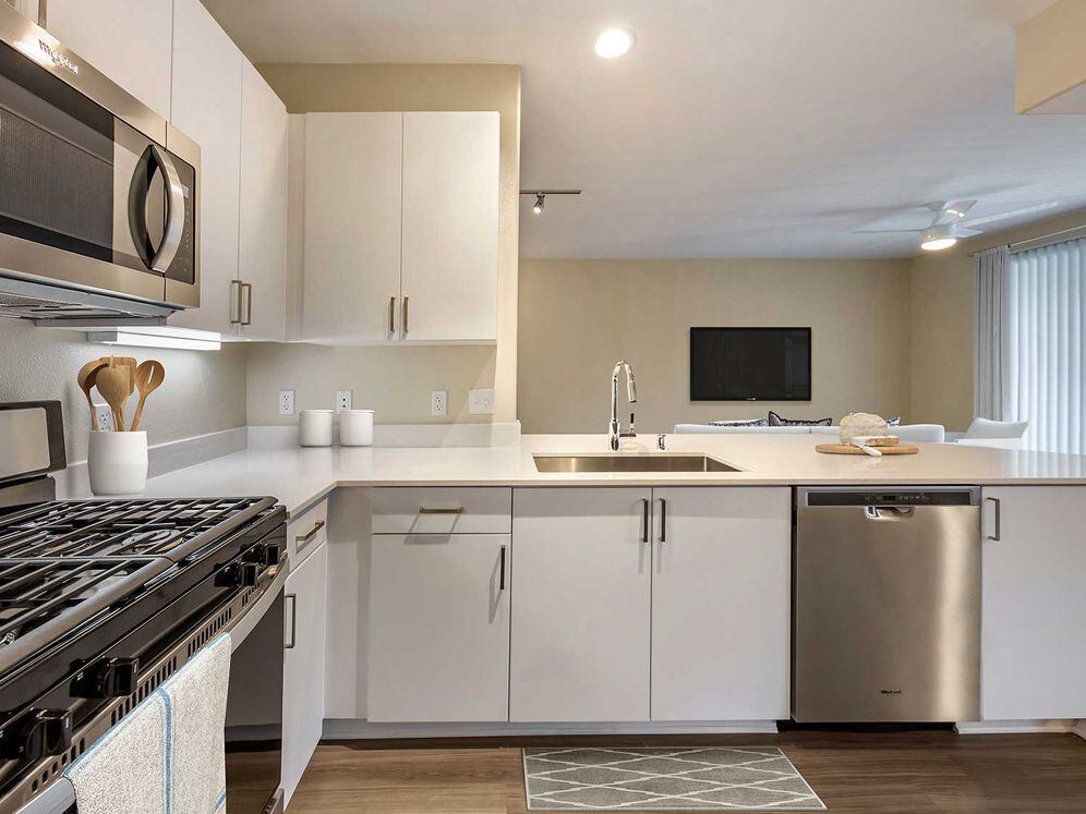 Renovated Package I kitchens with light grey quartz countertops, new white cabinetry, stainless steel appliances, upgraded fixtures, and hard surface flooring throughout