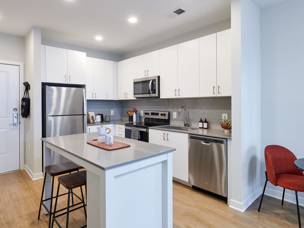 Design Collection II kitchen with white cabinetry, grey tile backsplash, grey quartz countertops, and stainless steel appliances