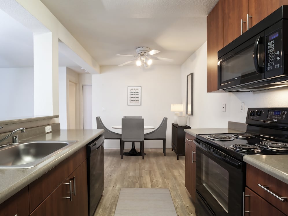 Classic Package kitchen with black appliances, dark grey laminate countertops, cherry cabinetry,  and hard surface flooring