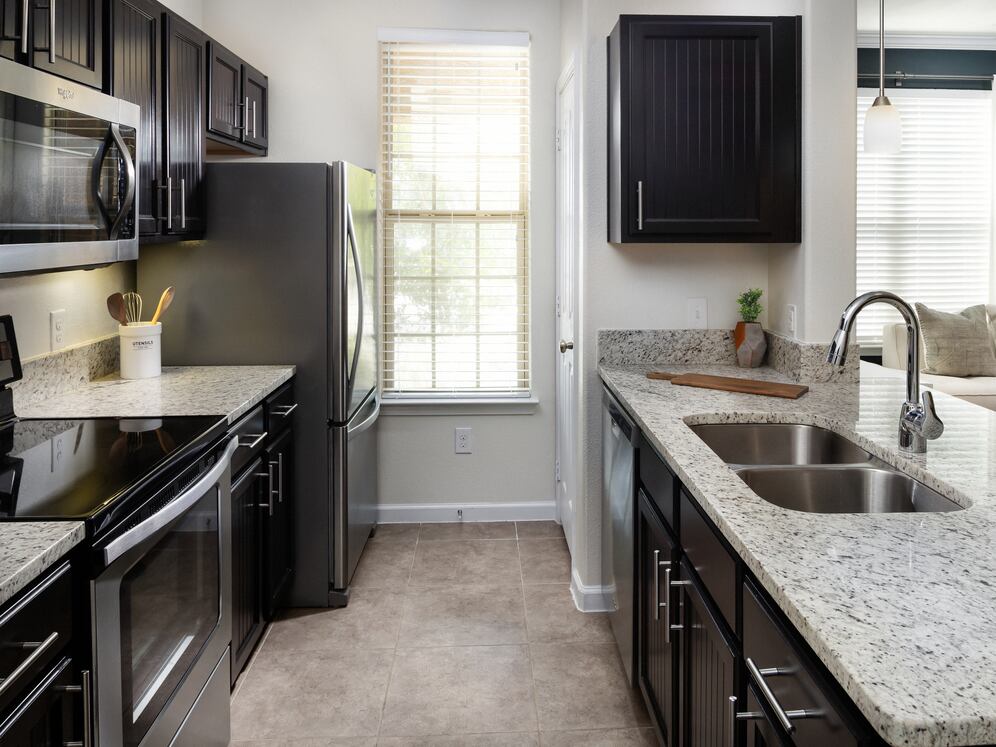 Kitchen with espresso cabinetry, granite countertops, and stainless steel appliances
