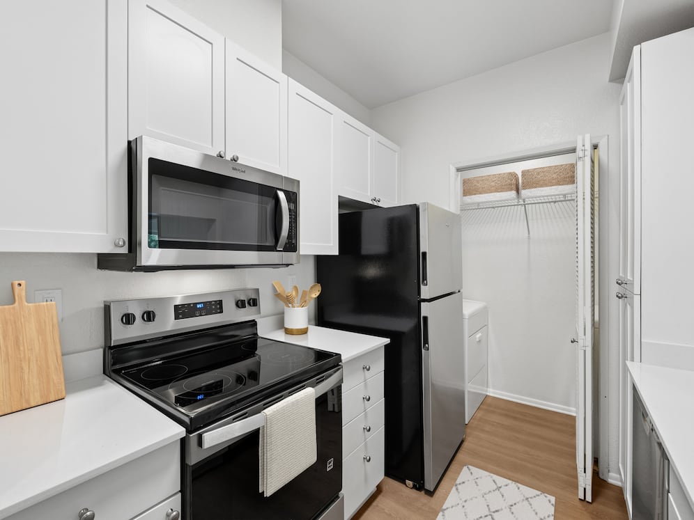 Renovated Package I kitchen with updated stainless steel appliances, white cabinetry, white quartz countertops, and hard surface flooring