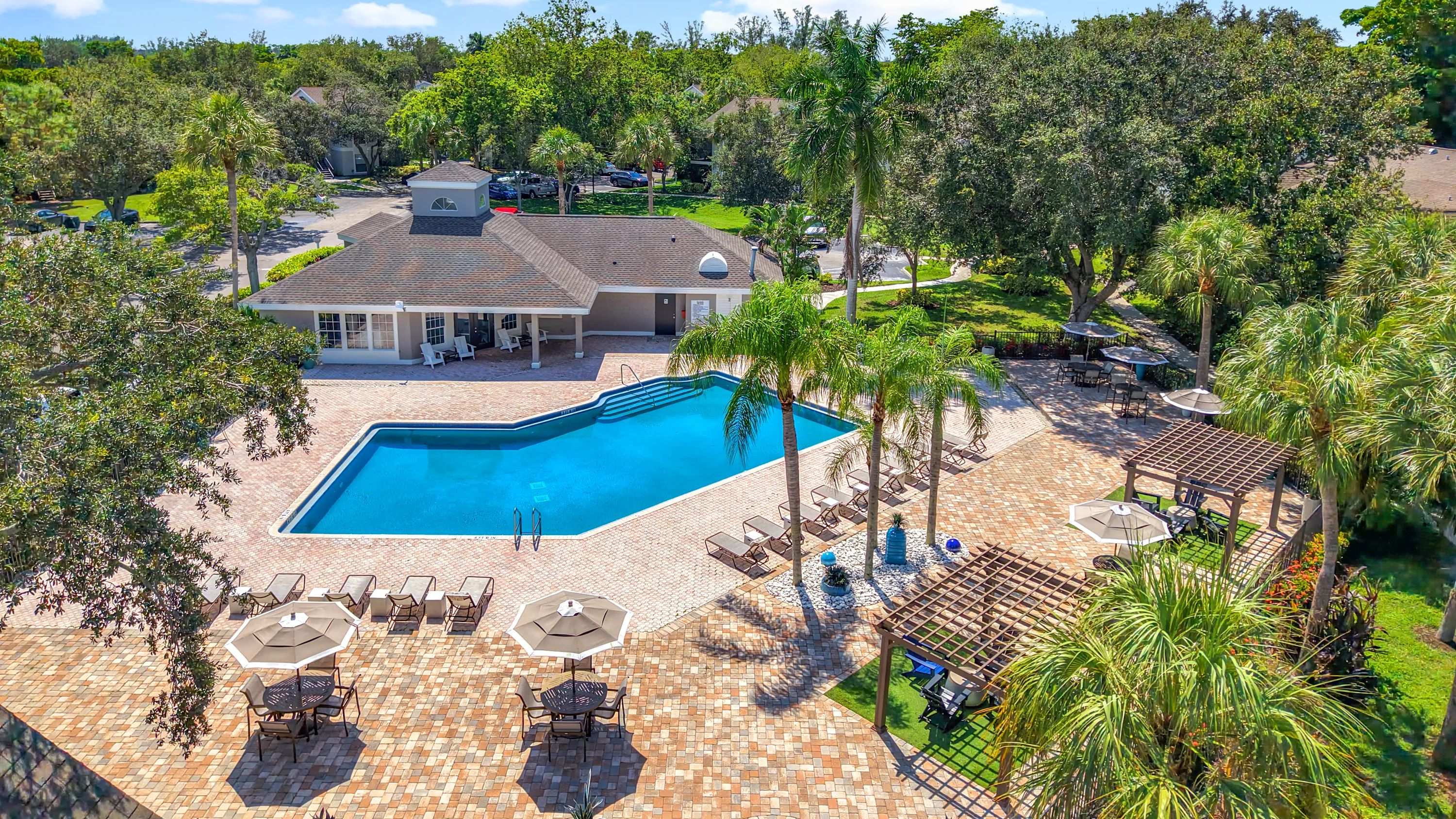 This vibrant bird’s-eye view shows off the beautifully maintained pool deck, shaded seating areas, and lush greenery that define River Reach’s outdoor oasis.