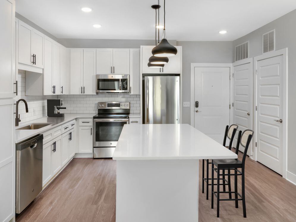 Modern kitchen with white cabinetry, white quartz countertops, and stainless steel appliances