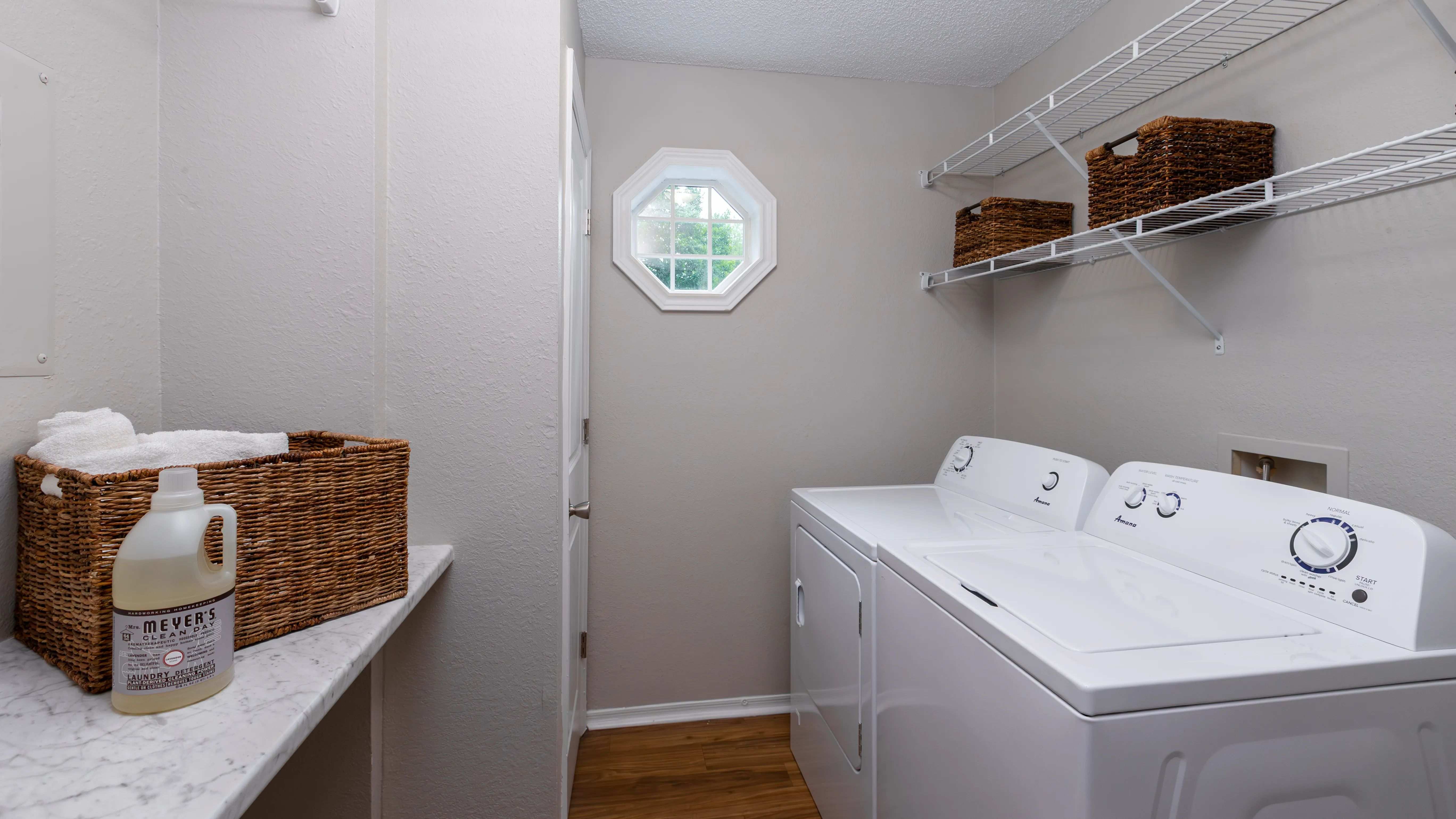Enjoy the comfort of a private laundry room featuring full-size appliances, overhead storage, and a window that brings in plenty of natural light.