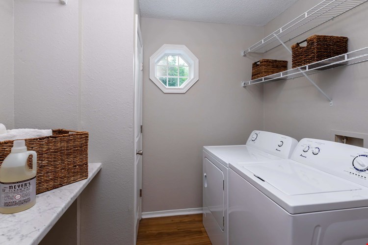Enjoy the comfort of a private laundry room featuring full-size appliances, overhead storage, and a window that brings in plenty of natural light.
