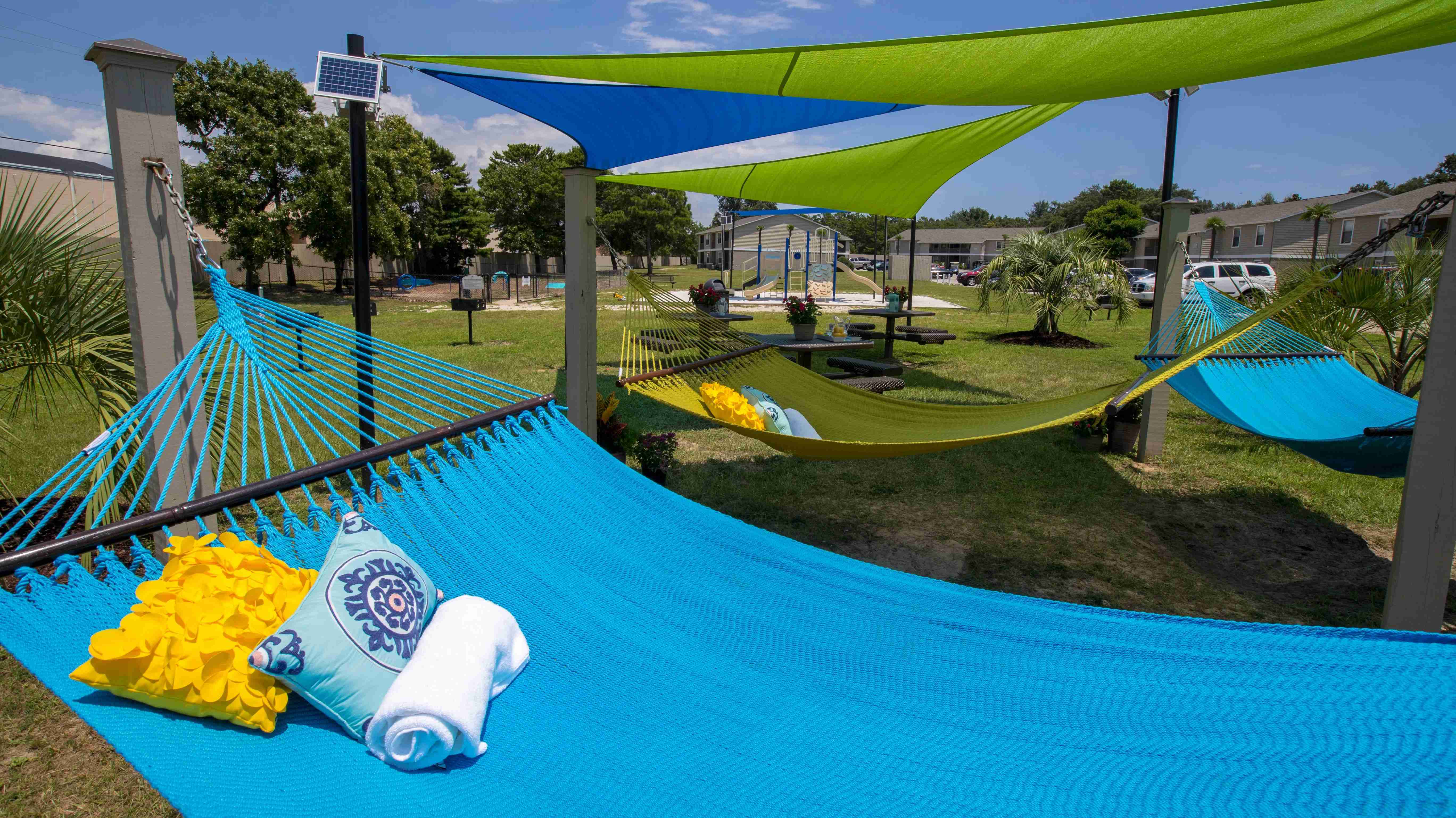 Unwind in our serene leisure area equipped with hammocks and picnic tables under colorful sail shades for an enjoyable outdoor experience.