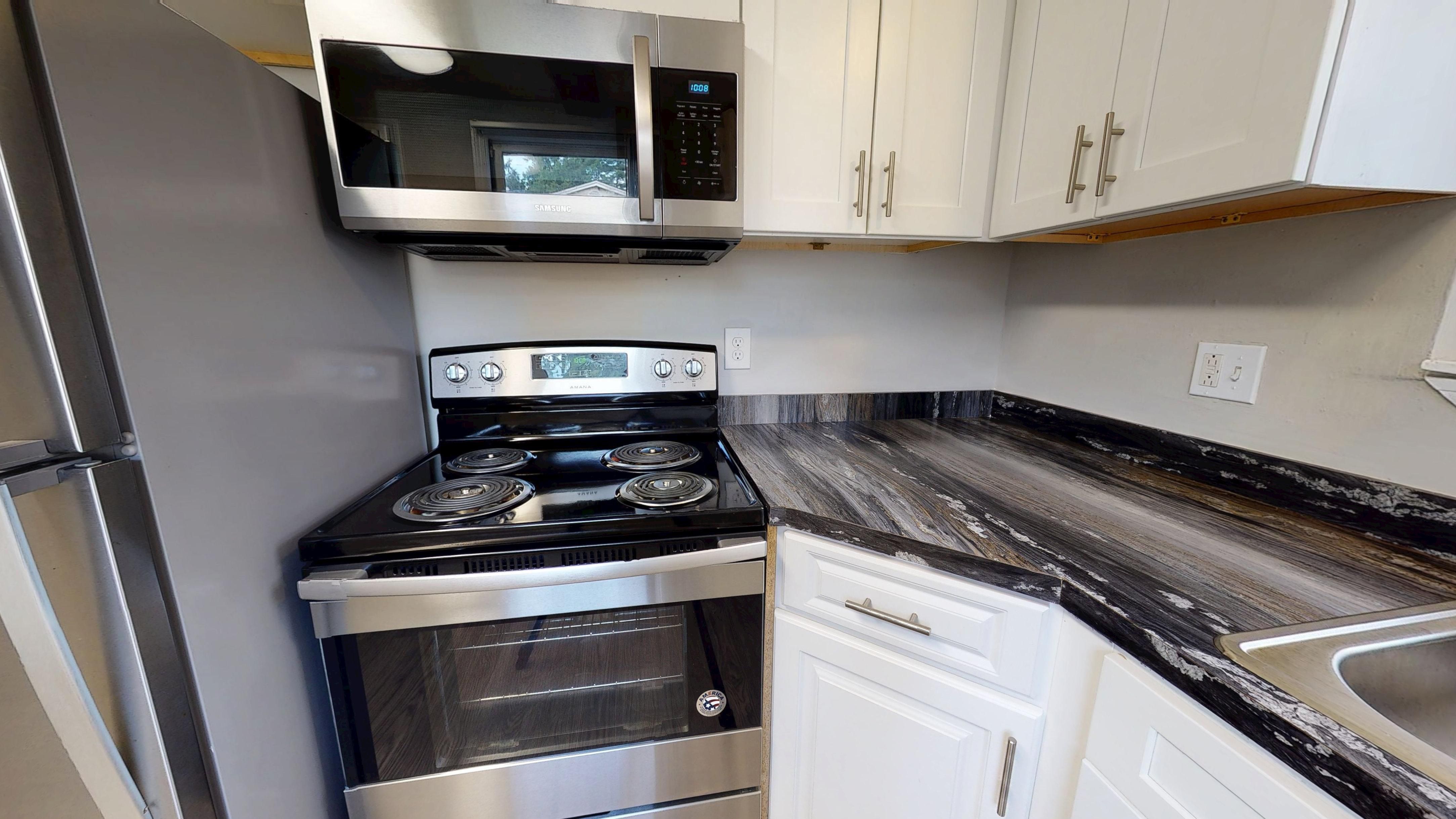 Whip up meals in style with The Hampshire's modern kitchen, featuring stainless steel appliances, white cabinetry, and black-fusion countertops.