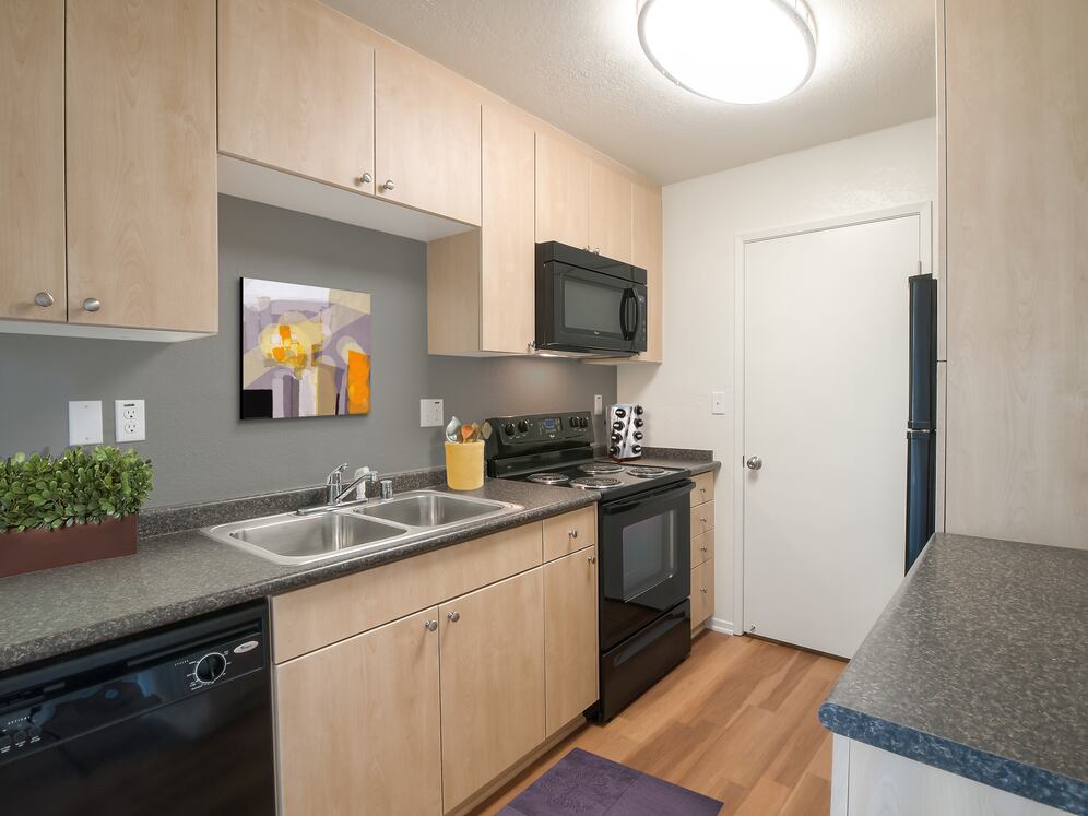 Classic Package I kitchen with black appliances, maple cabinetry, dark grey laminate countertops, and hard surface flooring