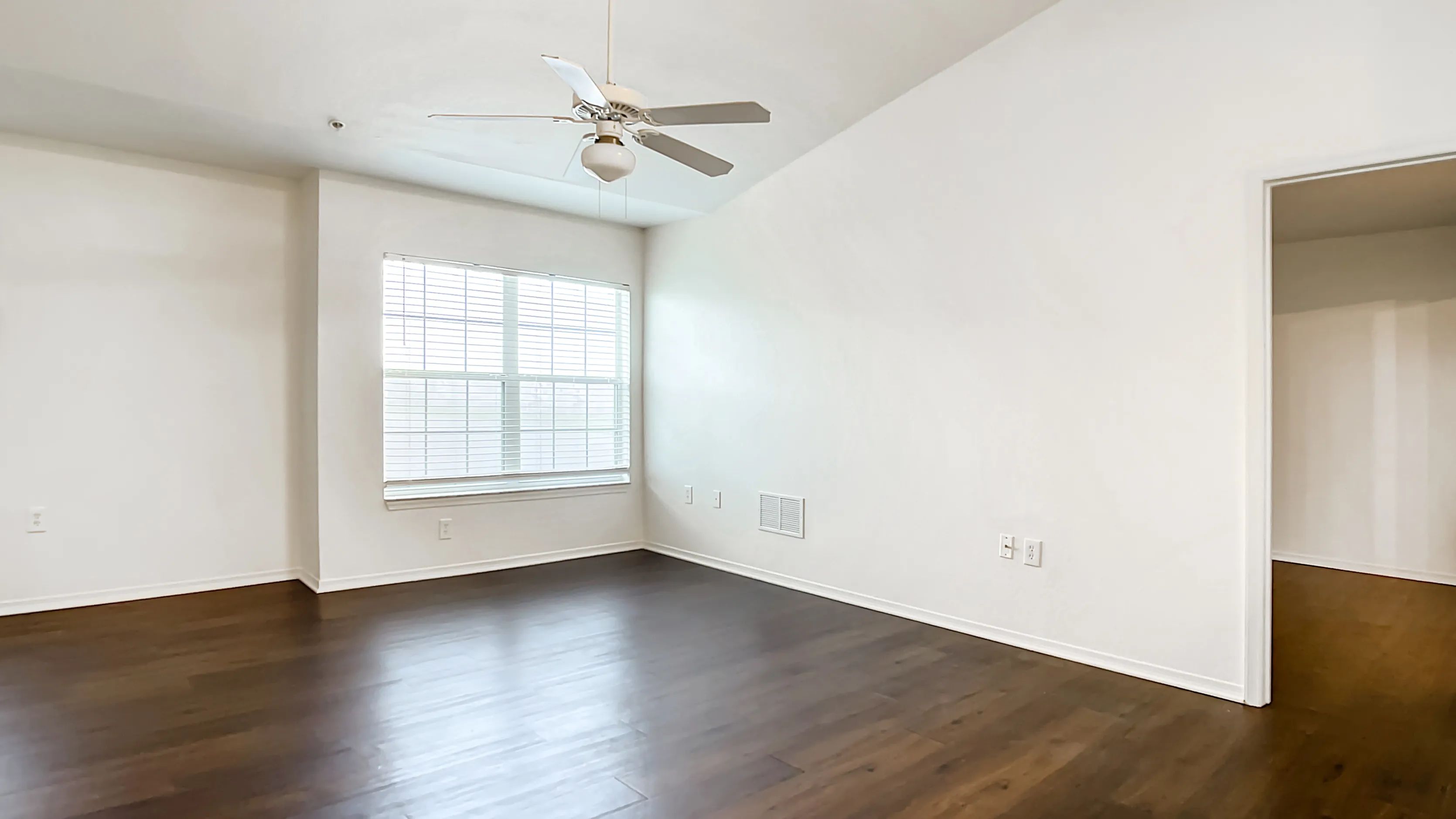 Live large and luxurious in your generous living area, where dark wood-style floors, a comforting ceiling fan, and a sizable window combine to create an inviting sanctuary.