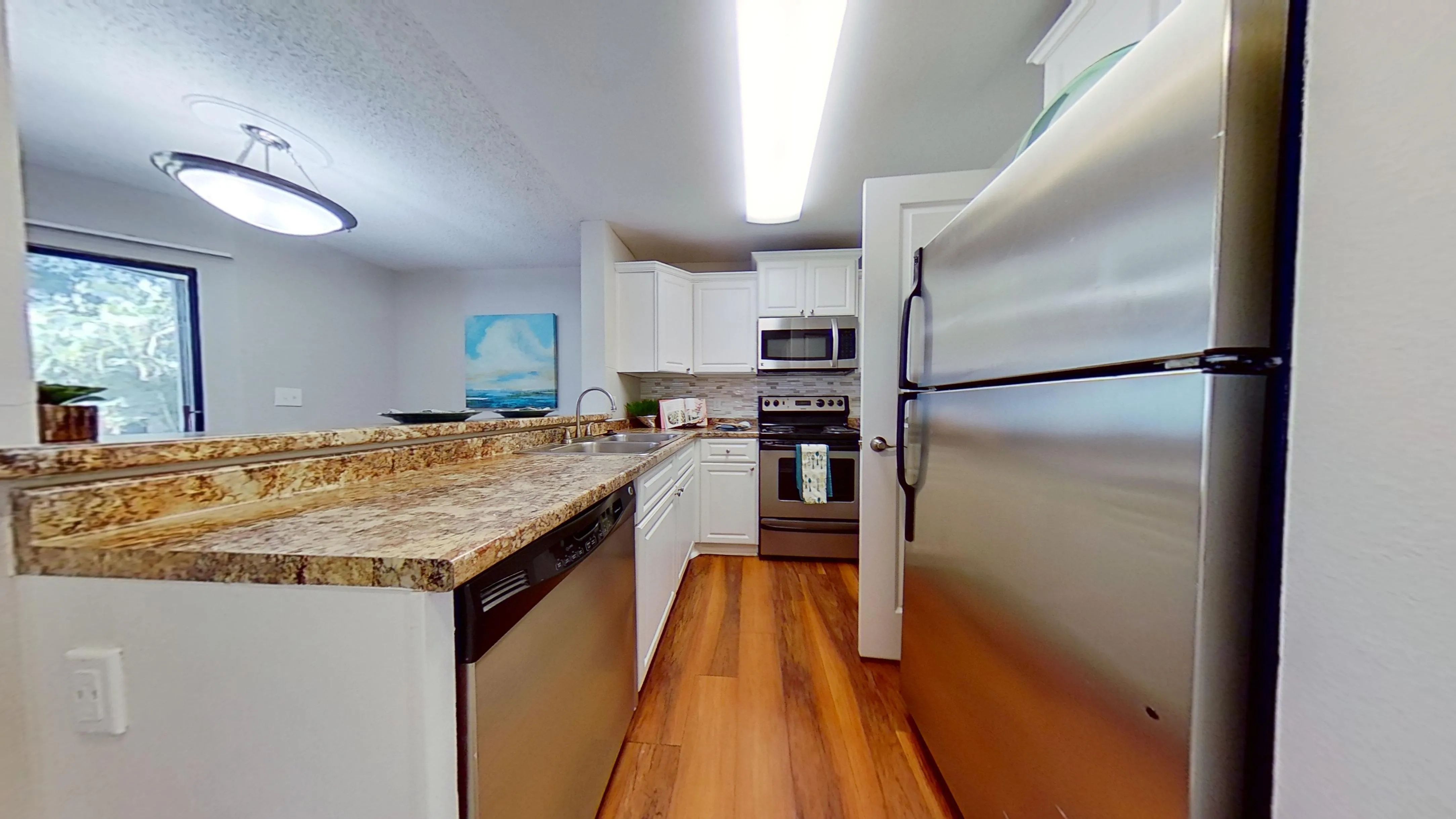 Enjoy a stylish kitchen in The Newport Autograph floor plan featuring stainless steel appliances, granite-style countertops, and a breakfast bar overlooking the living area.
