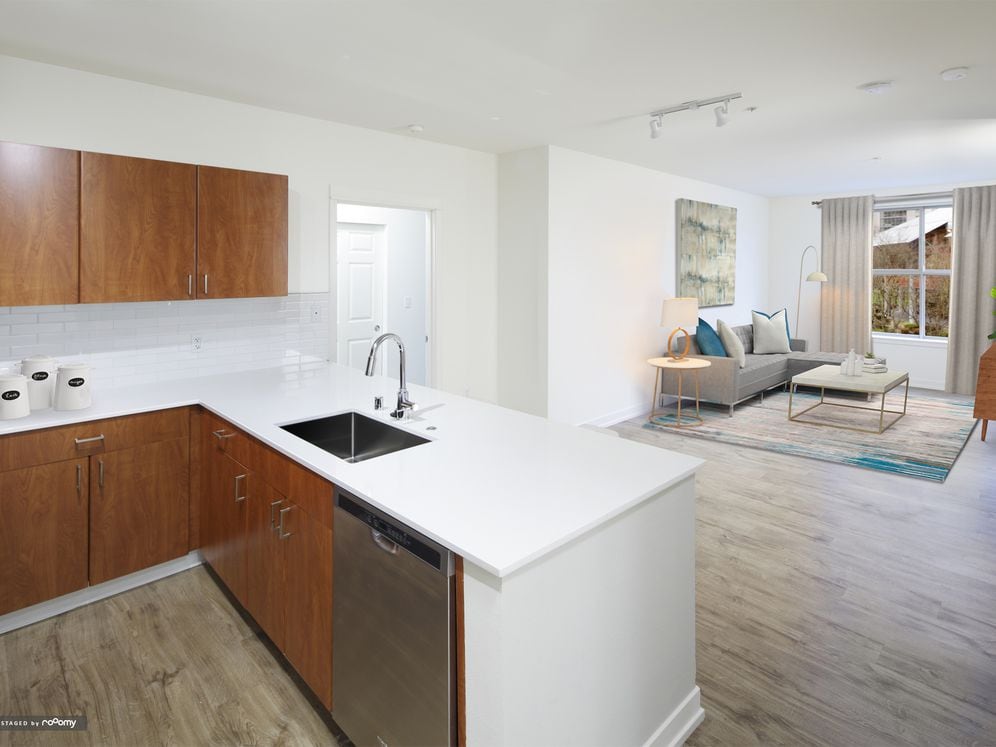 Renovated Package I kitchen and living area with white quartz countertops, oak cabinetry, stainless steel appliances, tile backsplash, and hard surface flooring