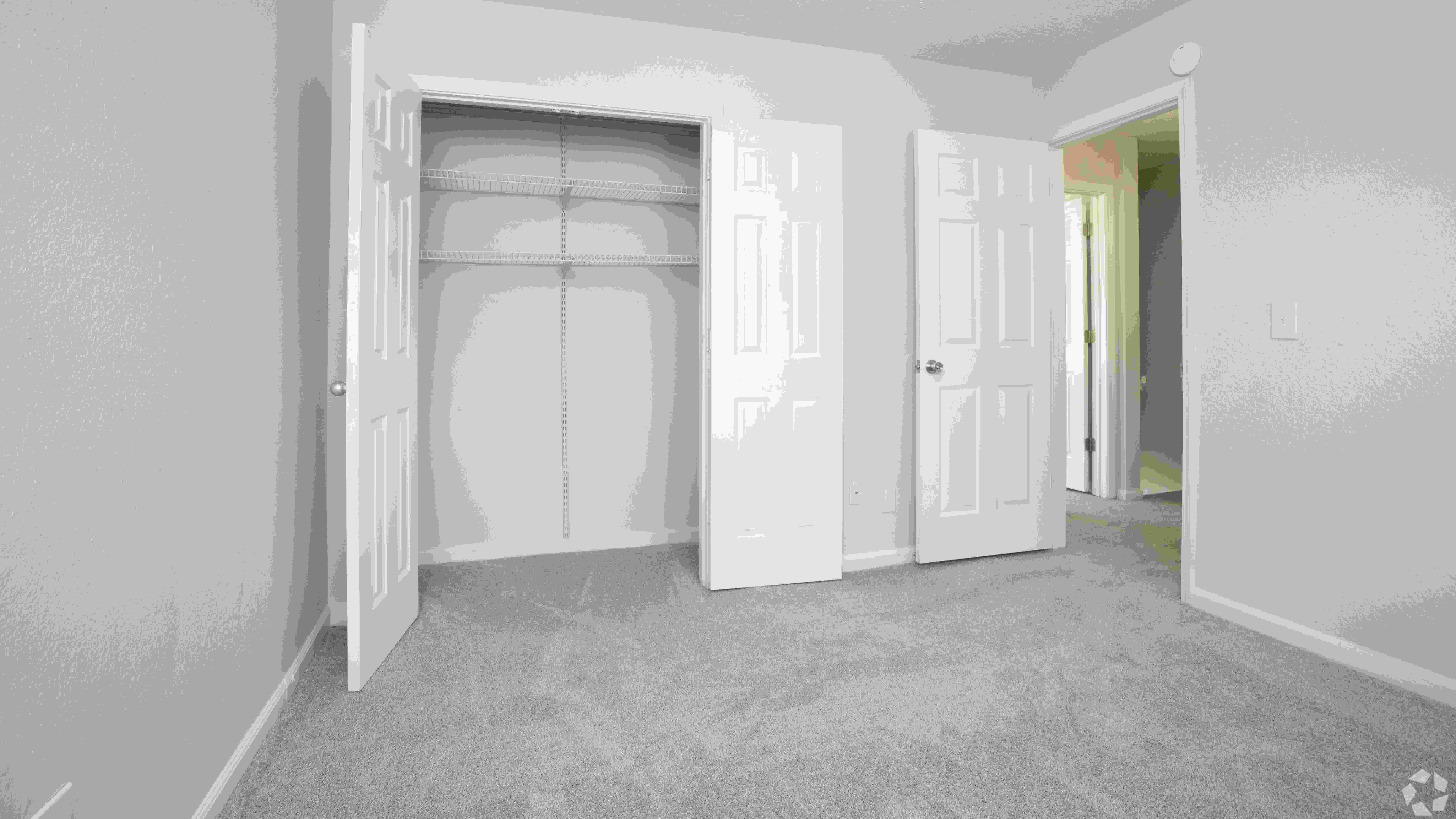 Spacious guest bedroom featuring a large closet with built-in shelving and plush carpeting, perfect for a cozy and inviting guest space.