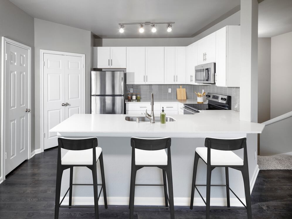 Classic Package II kitchen with stainless steel appliance, white quartz countertop, tile backsplash, white cabinetry, and hard-surface flooring