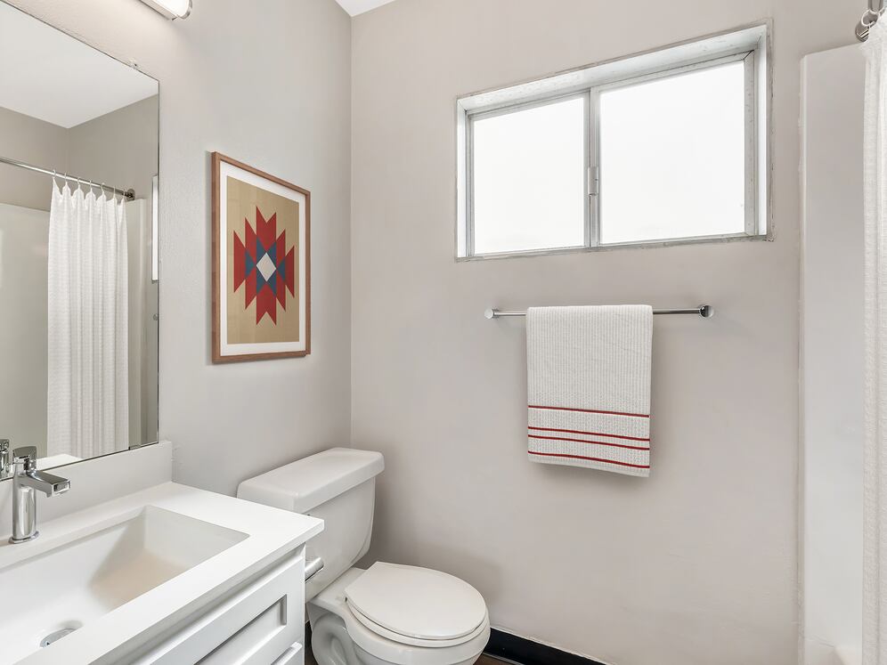 Renovated Package I bath with white quartz countertops, white cabinetry, and hard surface flooring (select homes)