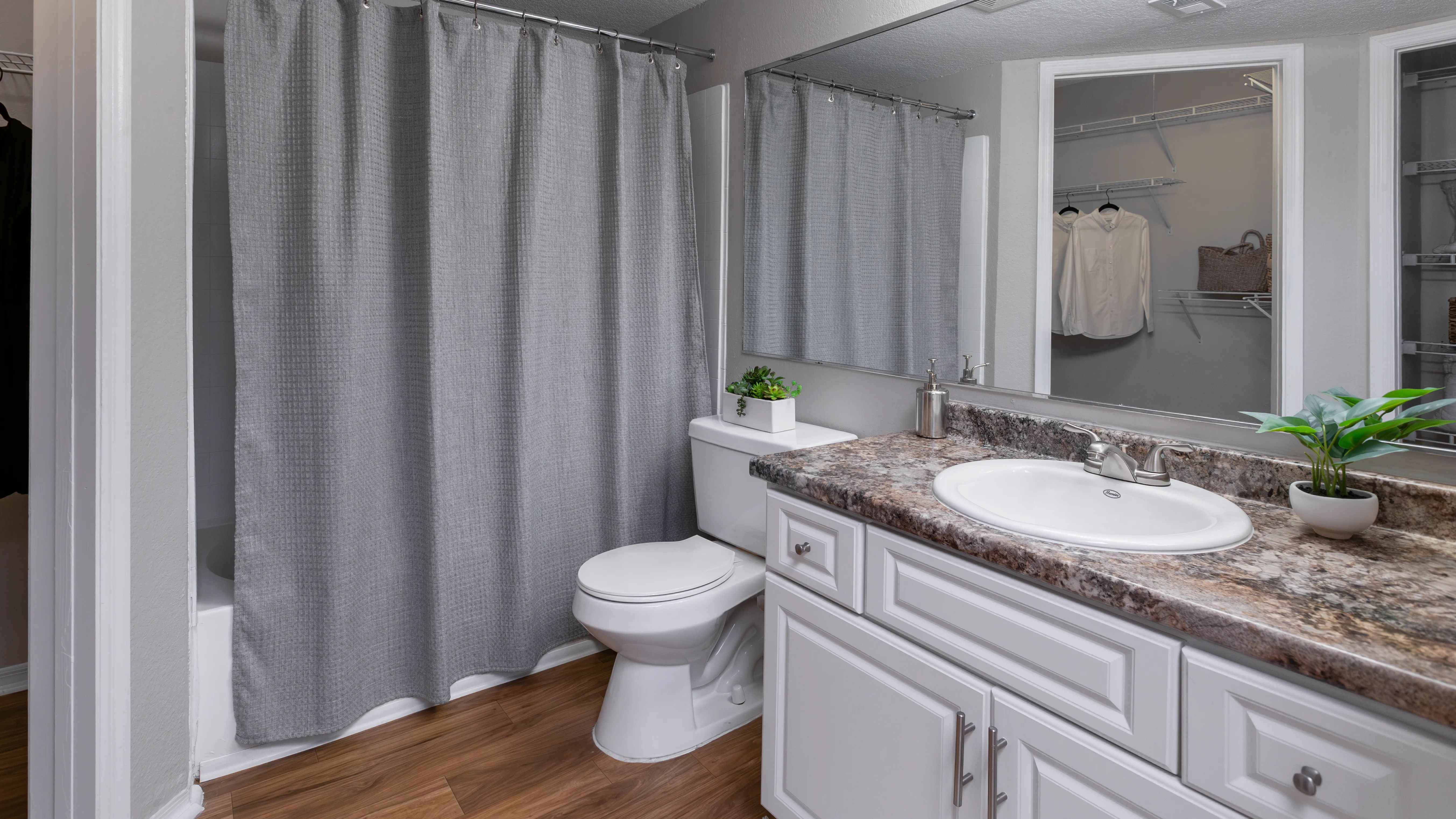 Enjoy a bright and inviting bathroom with sleek countertops, a large mirror, and stylish cabinetry.