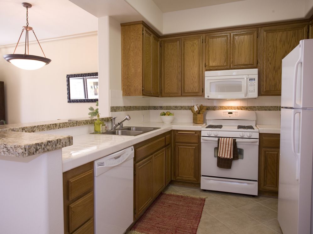 Classic Package I kitchen with white appliances, white tile countertop, oak cabinetry, and tile flooring