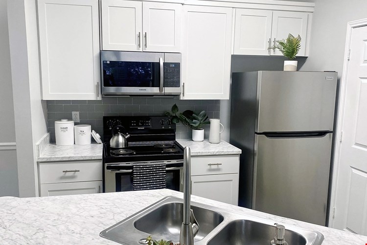 White cabinetry and stainless-steel appliances in our open-concept kitchens are complimented by Carrara marble inspired countertops in select homes.