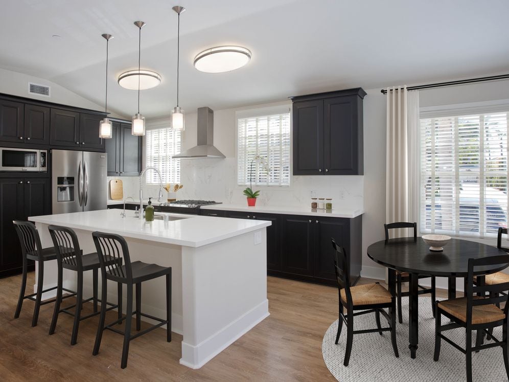 Kitchens with dark cabinetry, white quartz countertops, white tile backsplash, stainless steel appliances, and hard surface flooring