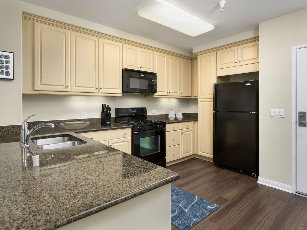 Classic Package I kitchen with black appliances, brown speckled granite, oak cabinetry, and hard surface flooring