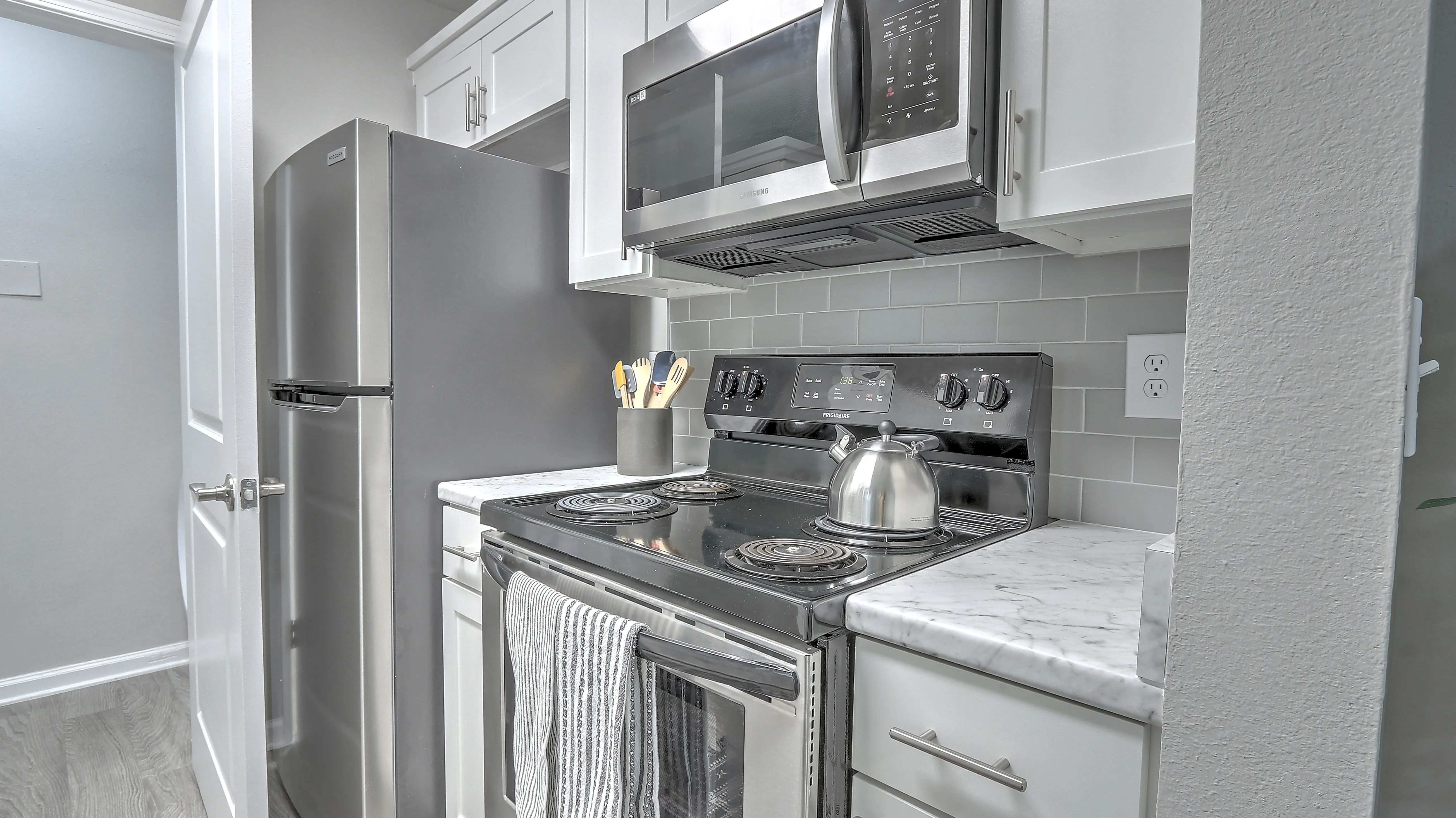 Kitchens with stylish appliances and a hip grey tile backsplash.