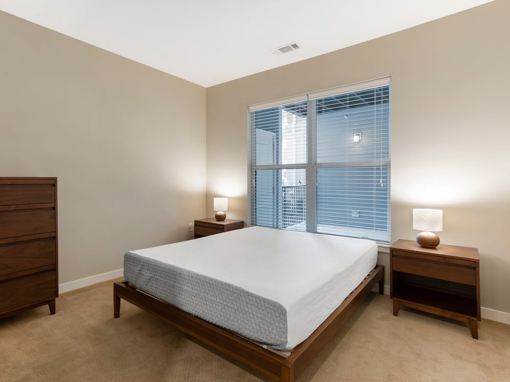 Furnished+ apartment homes feature queen bed with mattress, dresser, nightstands, and lamp (Representative Image – exact items and style of furnishings may vary)