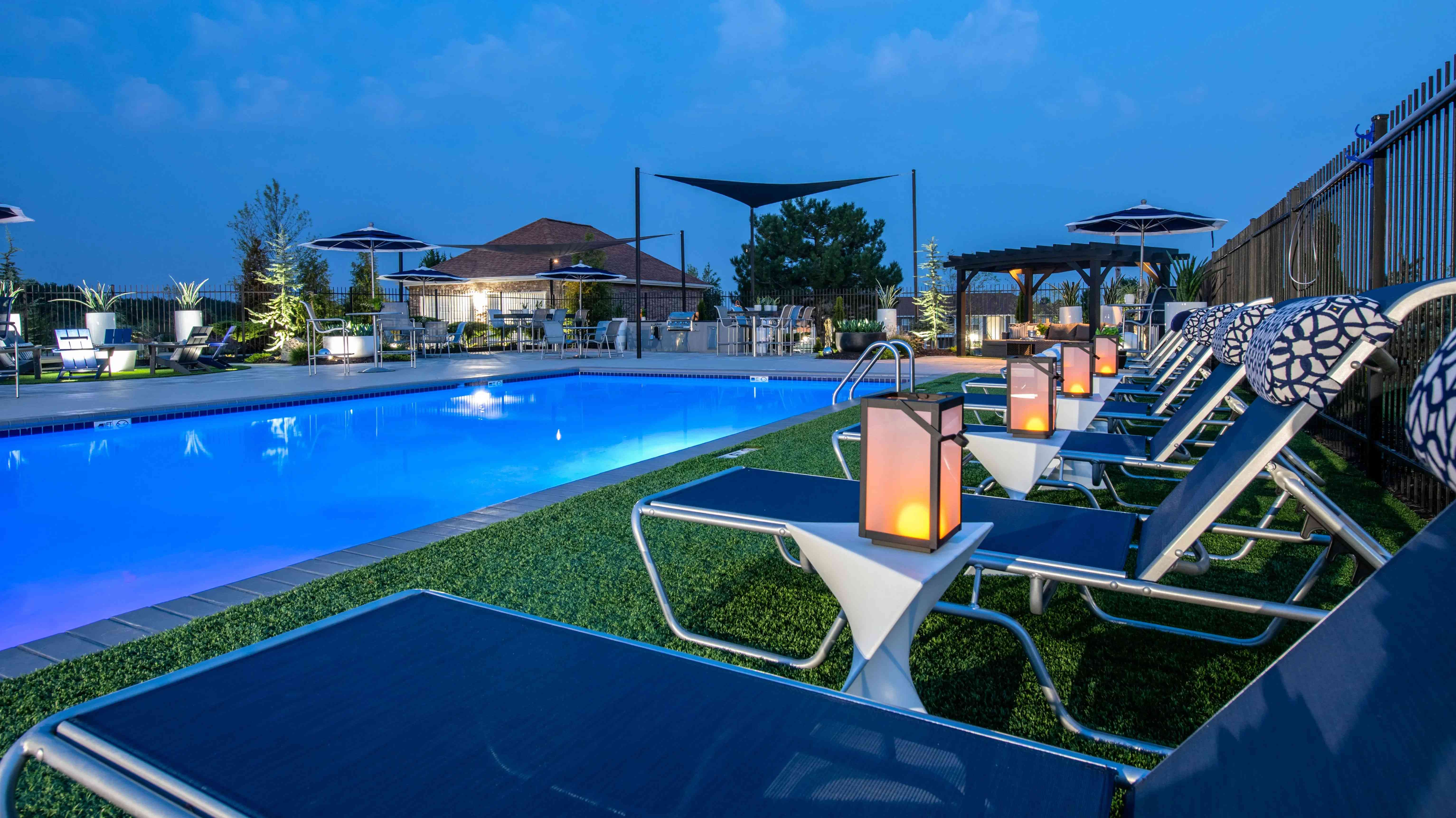 Embrace the vibrant ambiance of the pool deck at night, providing residents an enchanting space for solo relaxation or social enjoyment.