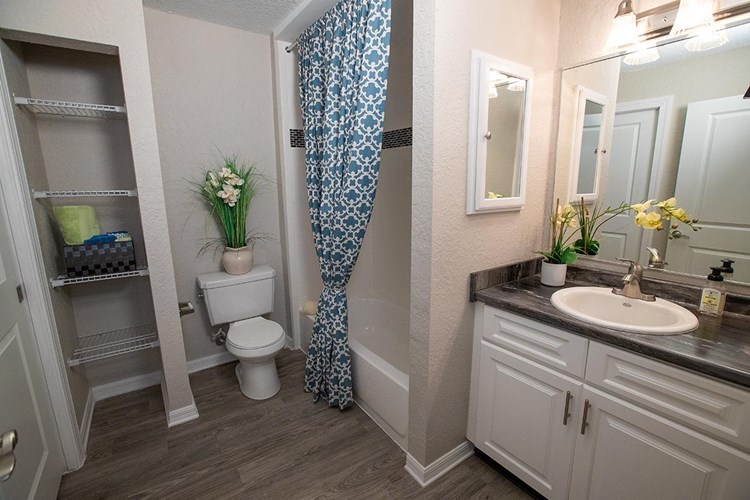 Newly renovated bathrooms featuring large mirrors, black fusion counter tops, and wood-style flooring.