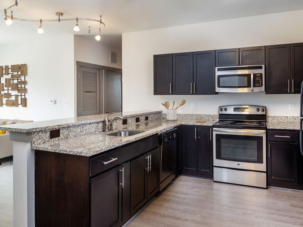 Classic Package II Kitchen with dark cabinetry, speckled granite countertops, white tile backsplash, stainless steel appliances, and hard surface flooring
