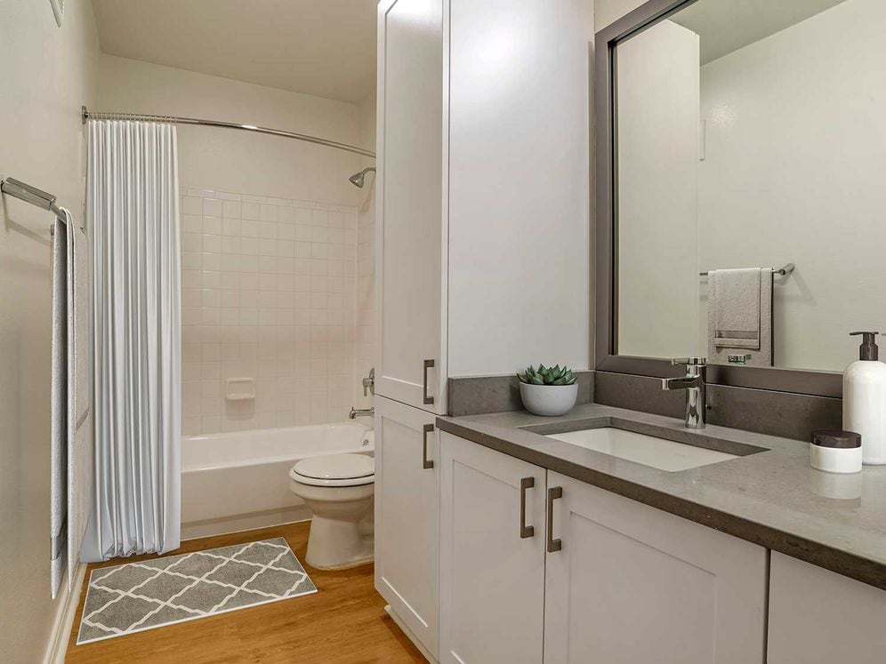 Renovated Package IV bath with white cabinetry, grey quartz countertops, and hard surface plank flooring