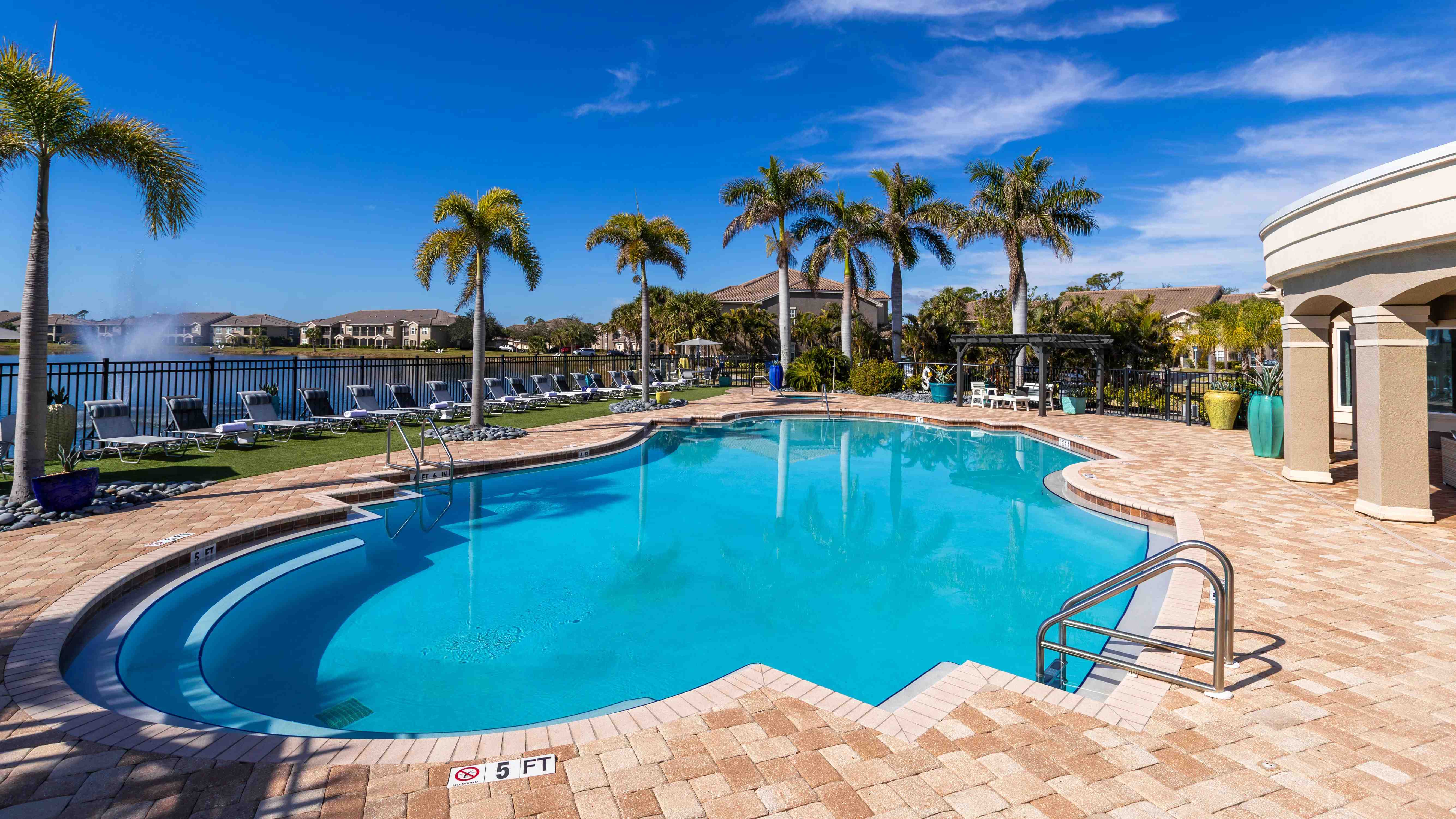 Enjoy the ultimate poolside experience with comfortable loungers, tropical landscaping, and a sparkling blue pool.