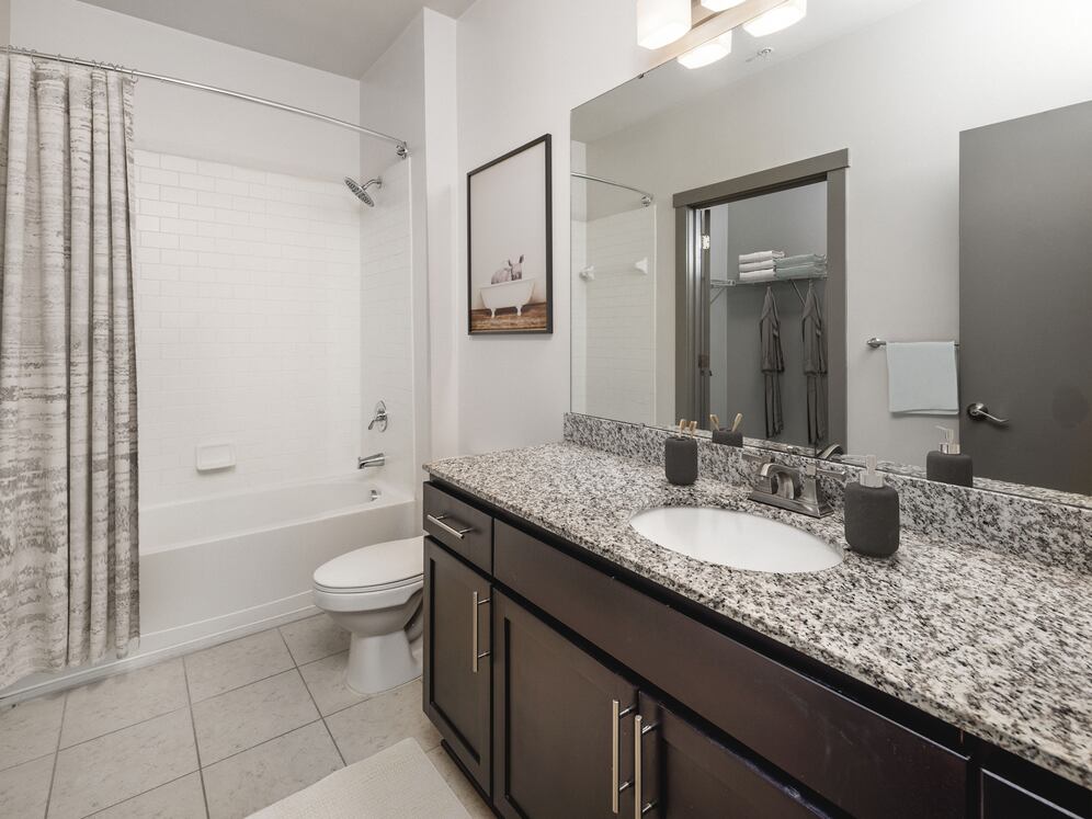 Classic Package II Bath with speckled granite countertop, dark wood cabinetry, and tile flooring