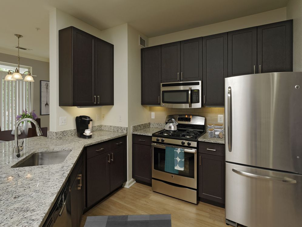 Renovated Package III kitchen with espresso cabinetry, granite countertops, stainless steel appliances, tile backsplash and hard surface flooring