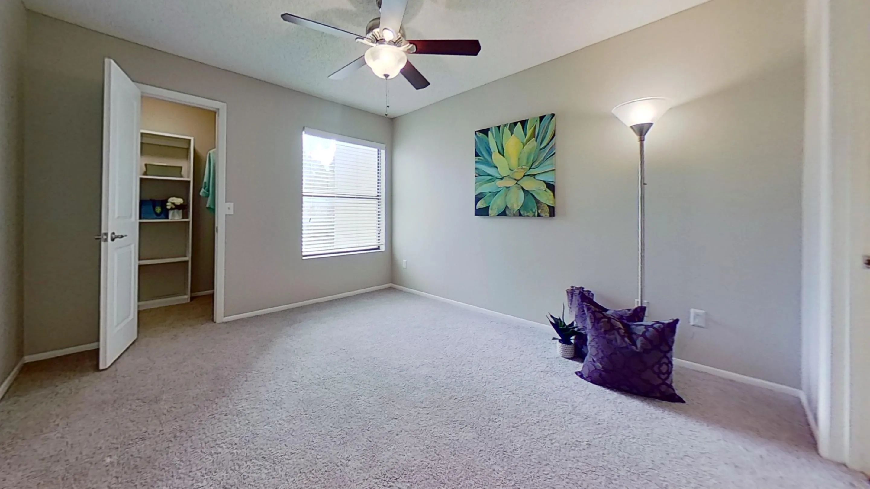 The Martinique Autograph floor plan offers a large bedroom with plush carpeting, a ceiling fan, and direct access to a walk-in closet.