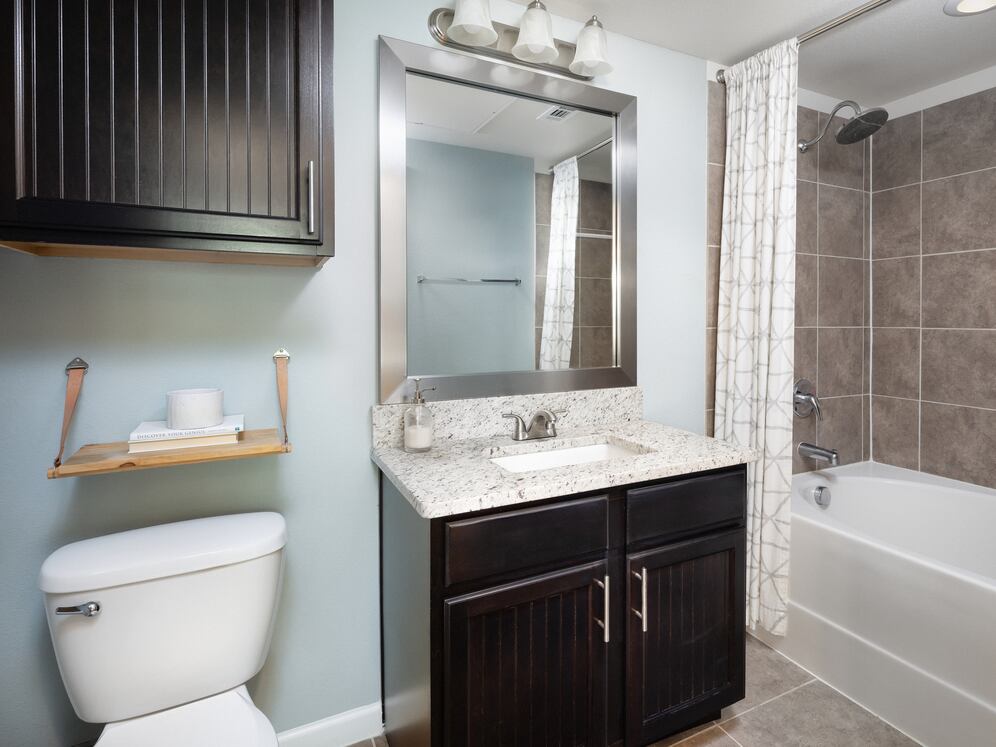 Bath with espresso cabinetry, granite countertop, and tile flooring