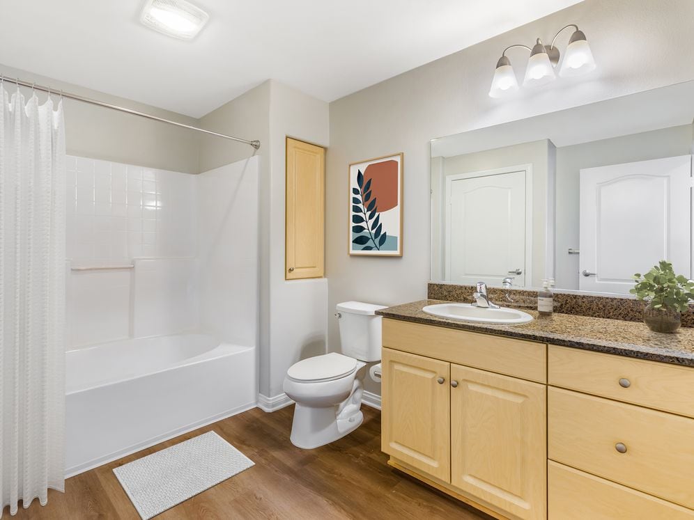 Classic Package II bath with oak cabinetry, dark granite countertops, and hard surface flooring